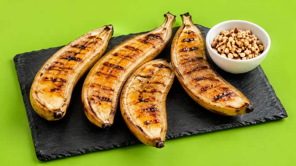 Grillede bananer skåret på langs med grillstriber på et mørkt skærebræt